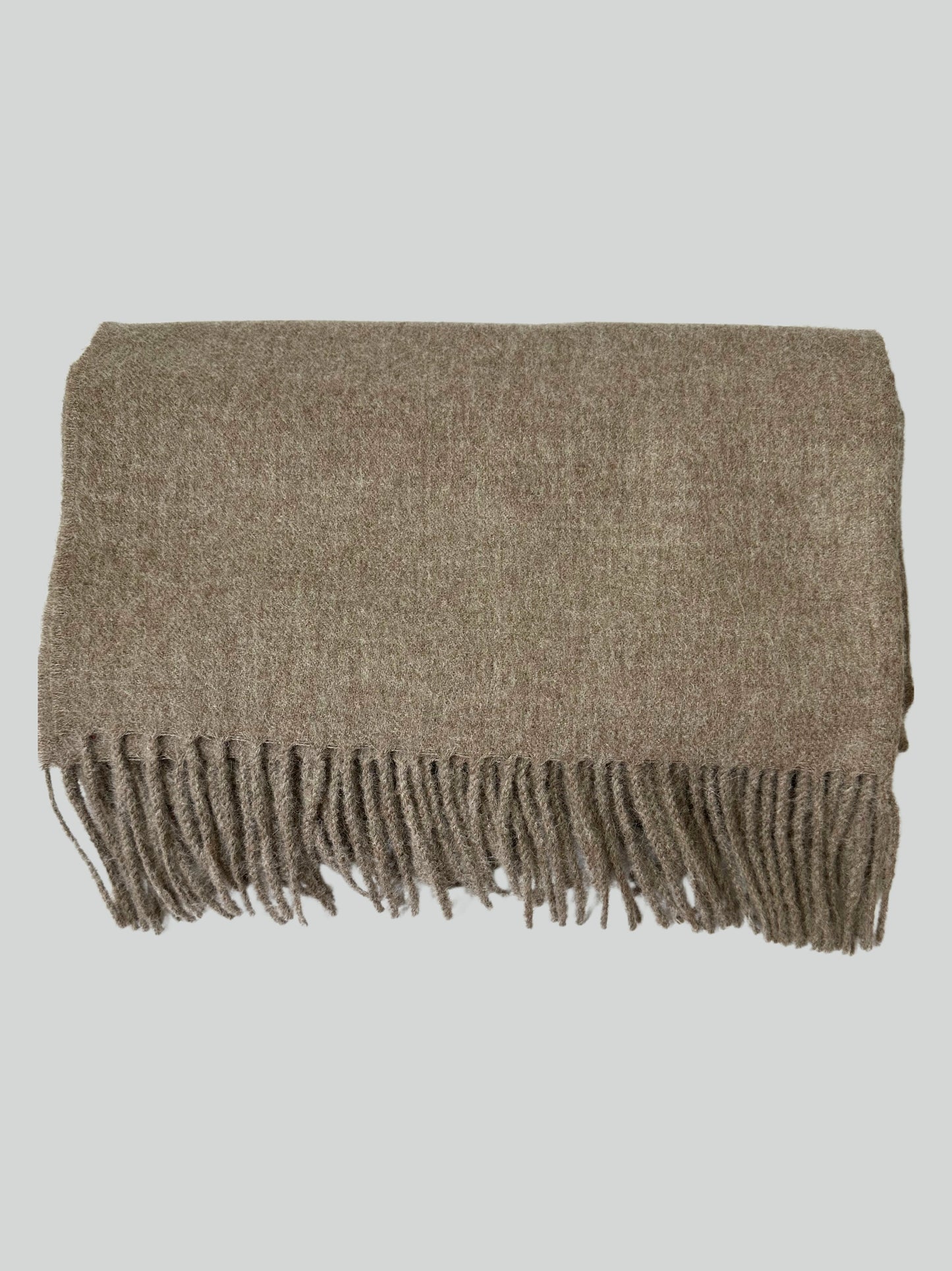 Cozy alpaca throw in light brown, draped over a modern sofa—ideal for winter warmth and stylish home décor.