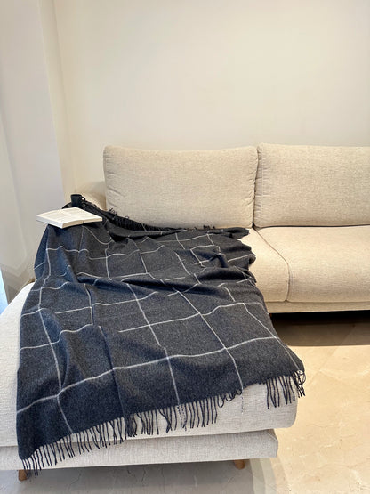 Elegant grey alpaca plaid blanket neatly folded on a sofa, a luxurious and cozy throw adding warmth and comfort to your home.