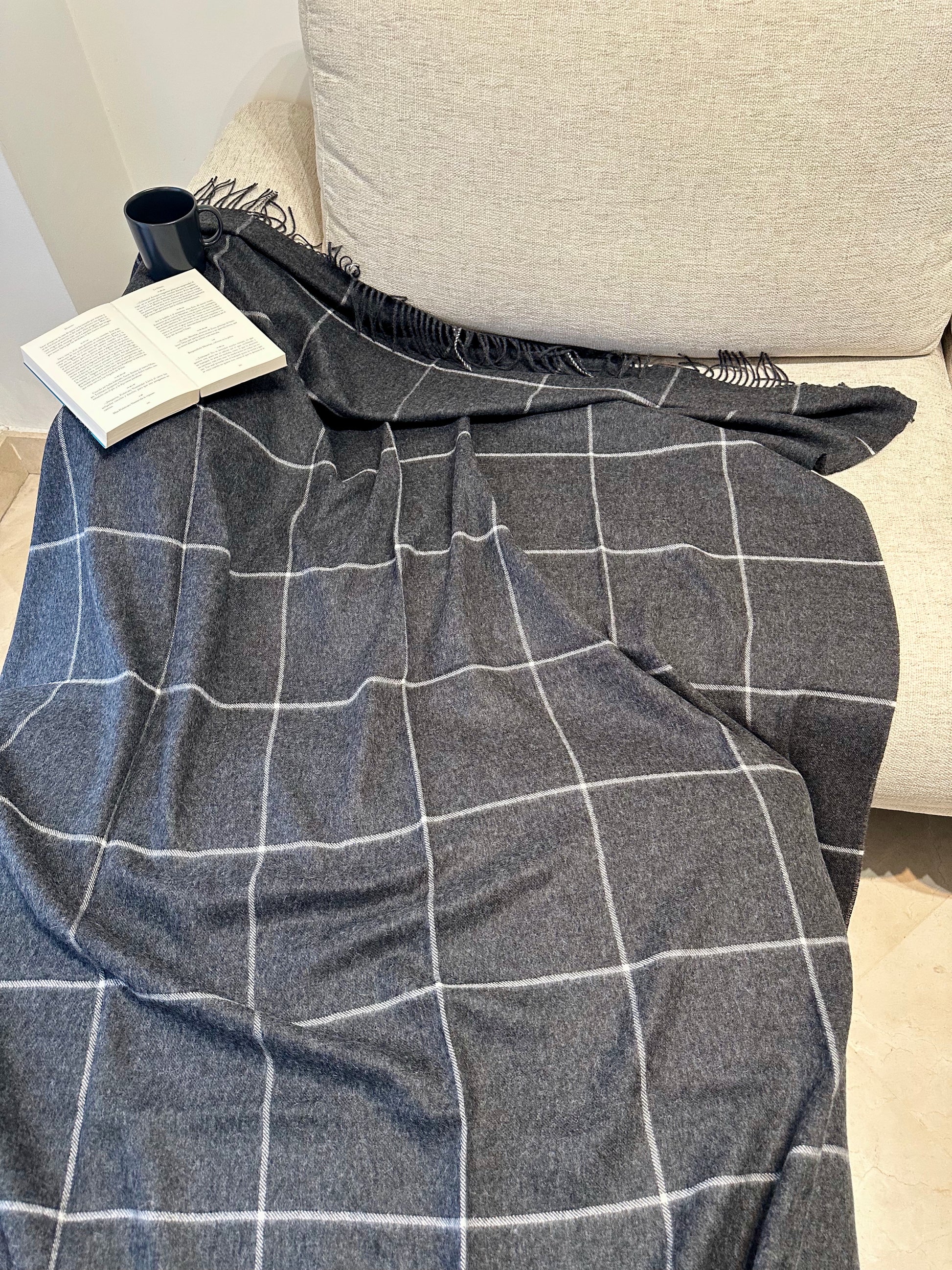 Manta de cuadros gris de alpaca natural, suave, cálida y elegante. Perfecta para sofá o cama, aporta confort y estilo atemporal al hogar.