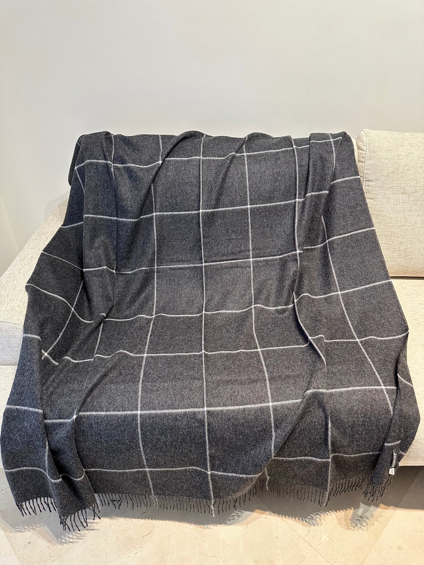 Plaid à carreaux gris en alpaga, élégant et chaud, parfait pour canapé ou lit, ajoutant confort et style à votre intérieur.