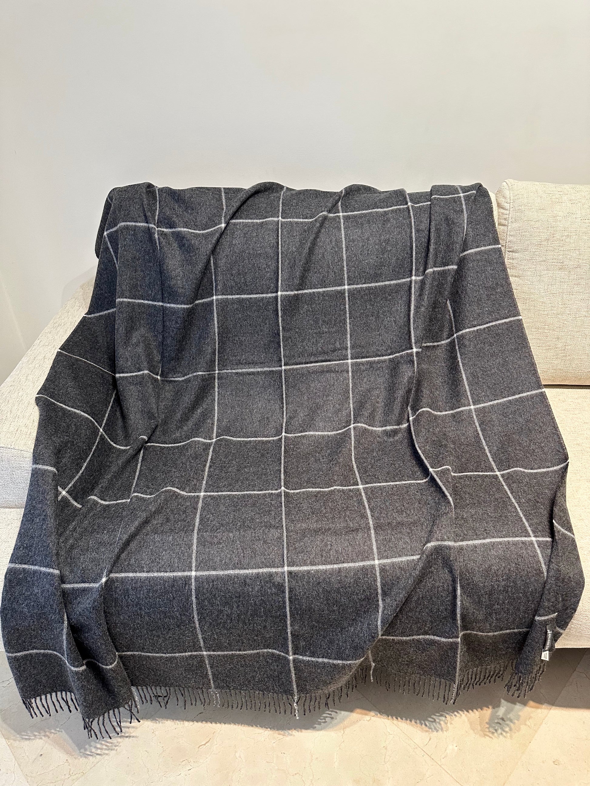 Plaid à carreaux gris en alpaga, élégant et chaud, parfait pour canapé ou lit, ajoutant confort et style à votre intérieur.